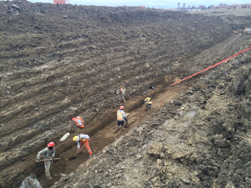 Construction crews work to backfill and compact sand over the sanitary sewer line.