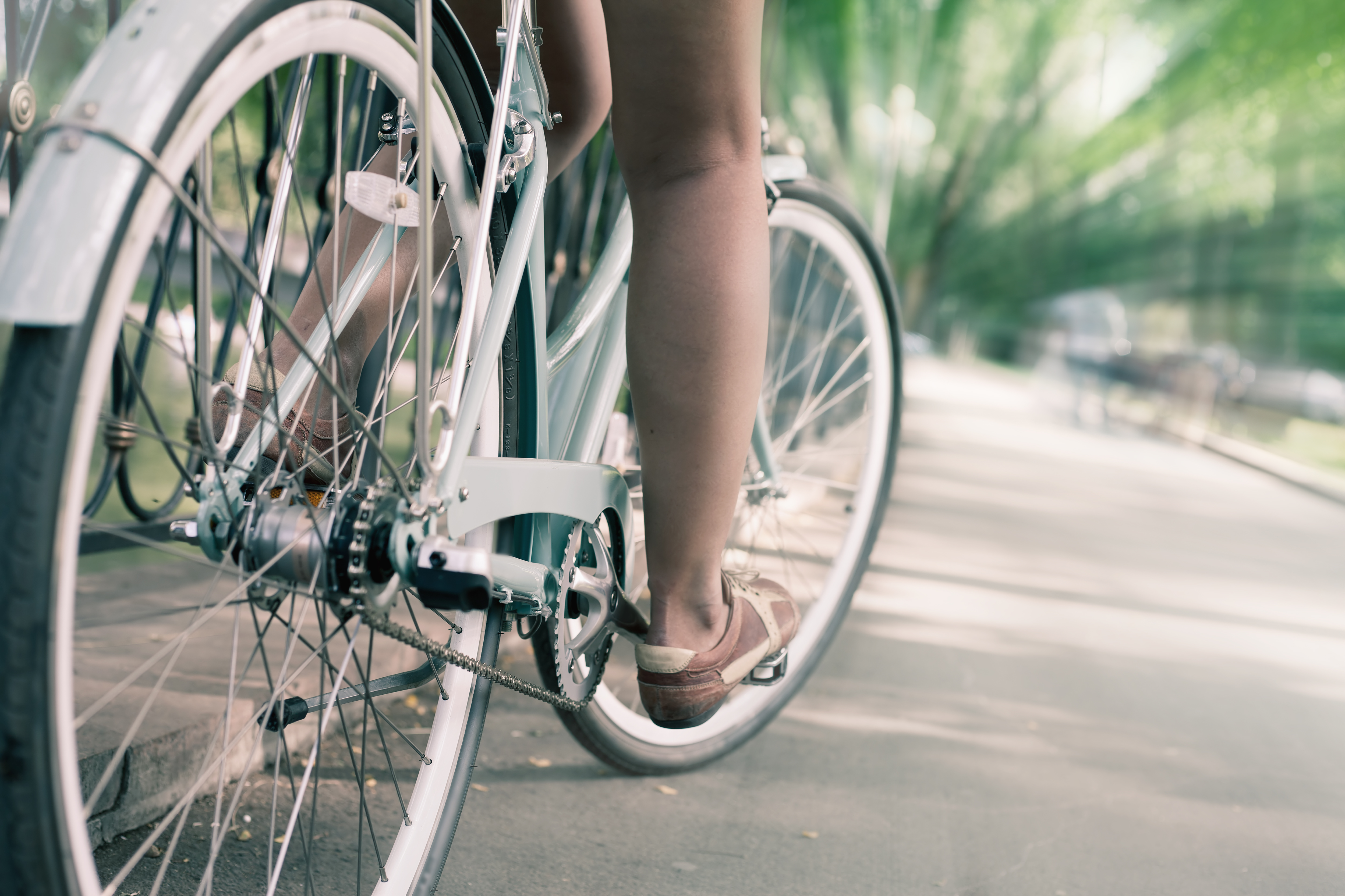 closeup of woman riding by blue vintage city bicycle at the city center with motion blur effect. It is like concept for activity and healthy lifestyle and environmentally friendly transport